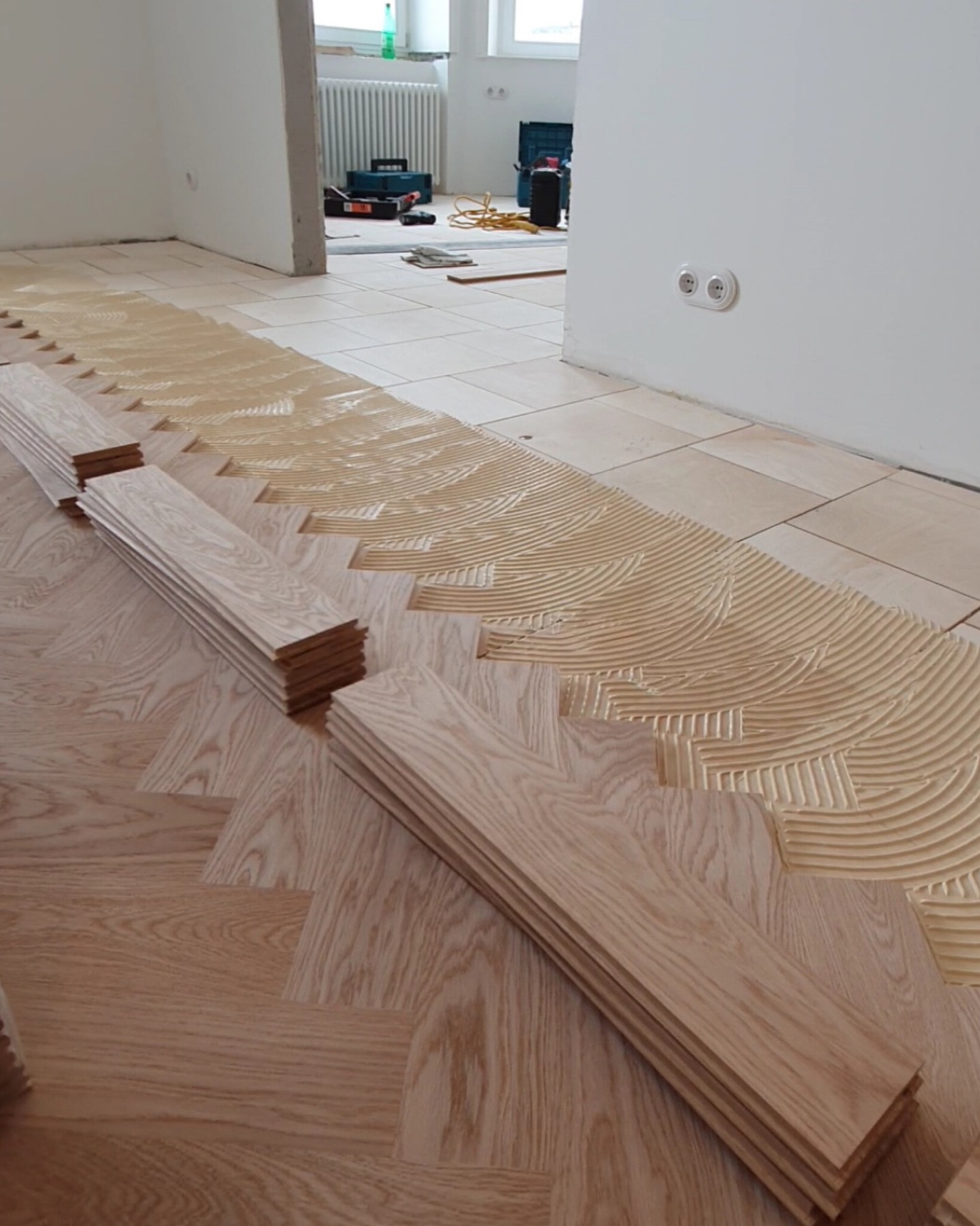 Herringbone parquet boards arranged over the adhesive bed before fixing