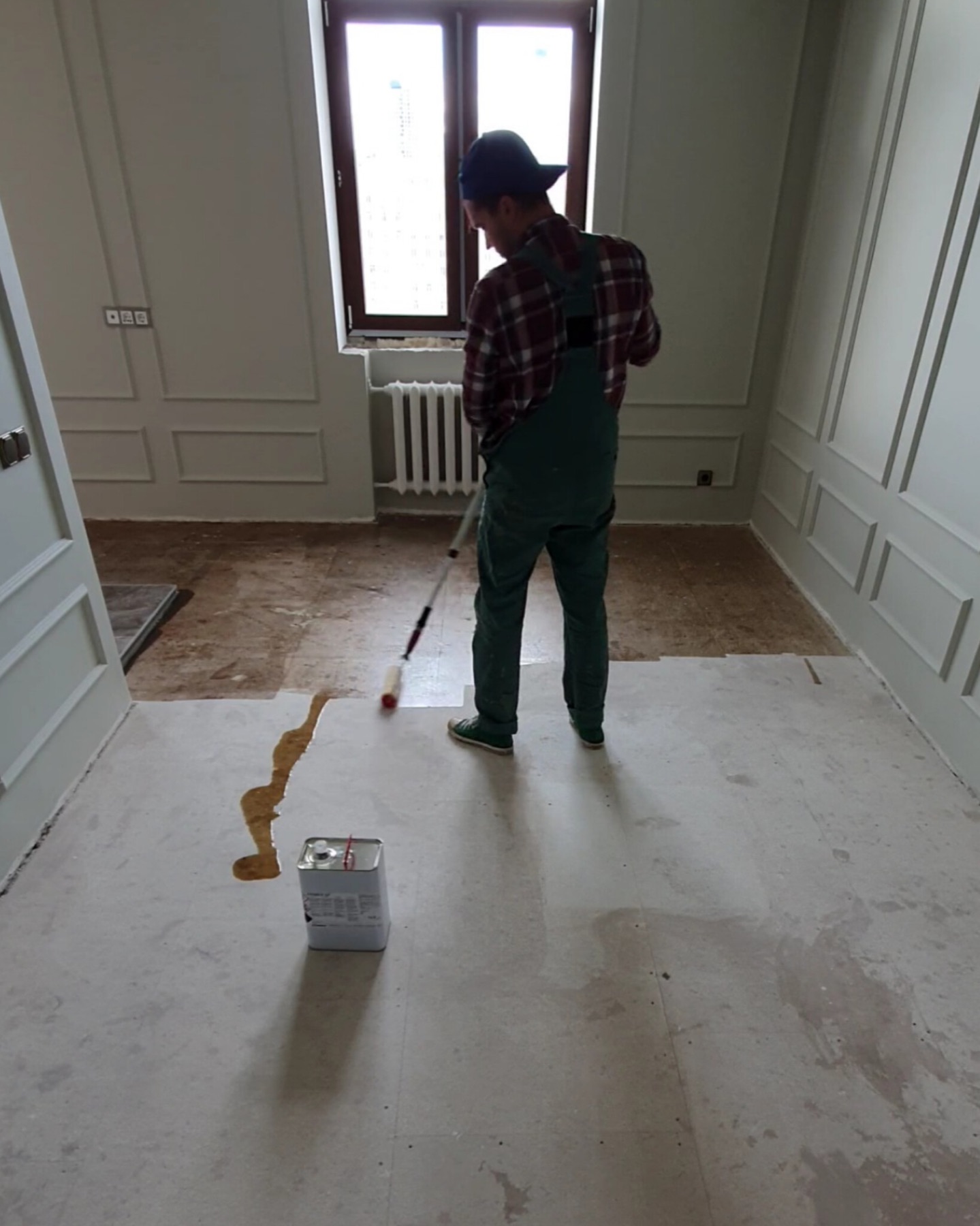 Priming the subfloor before plywood installation in the kitchen and dining area