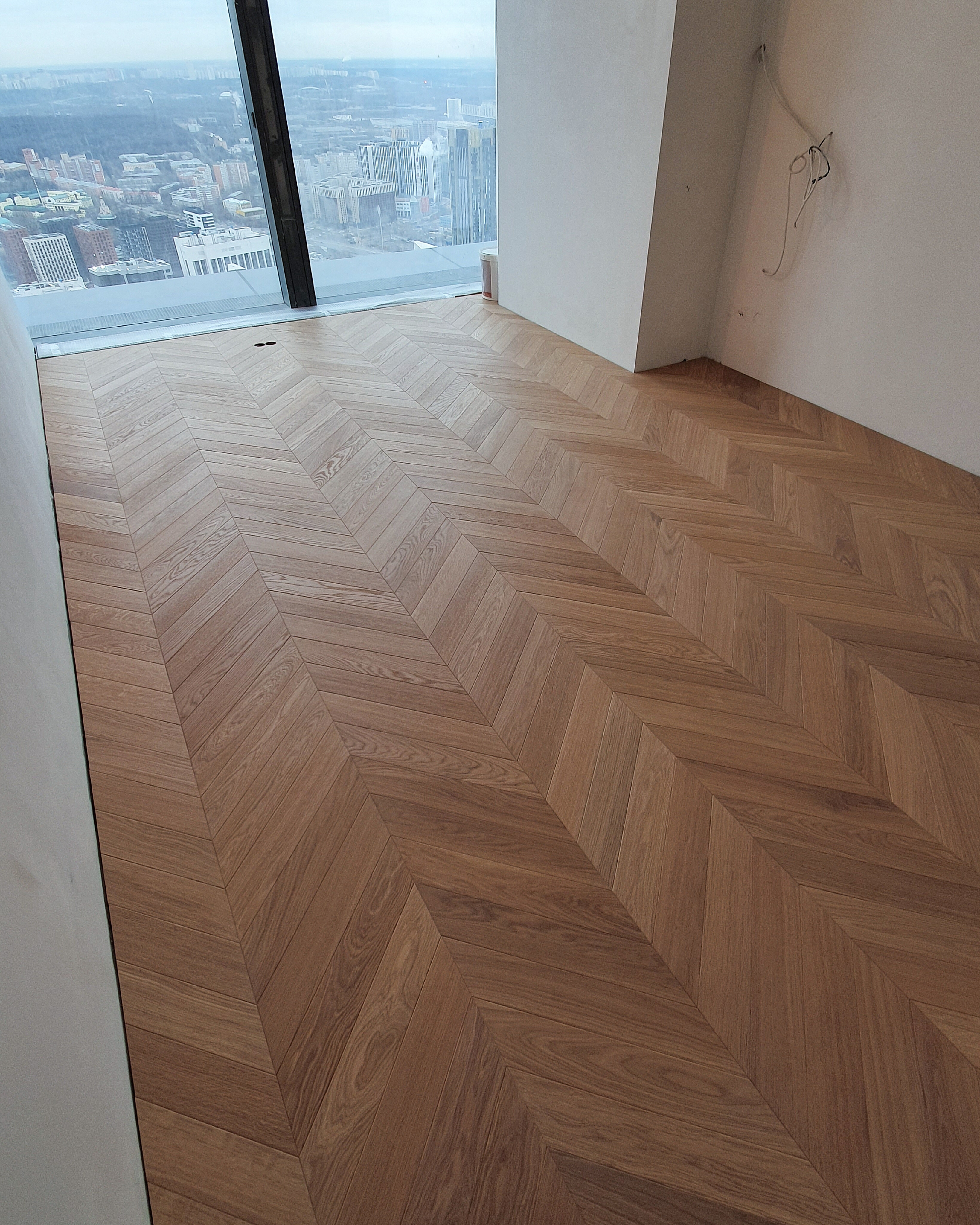 Finished French chevron parquet in a modern apartment with panoramic windows