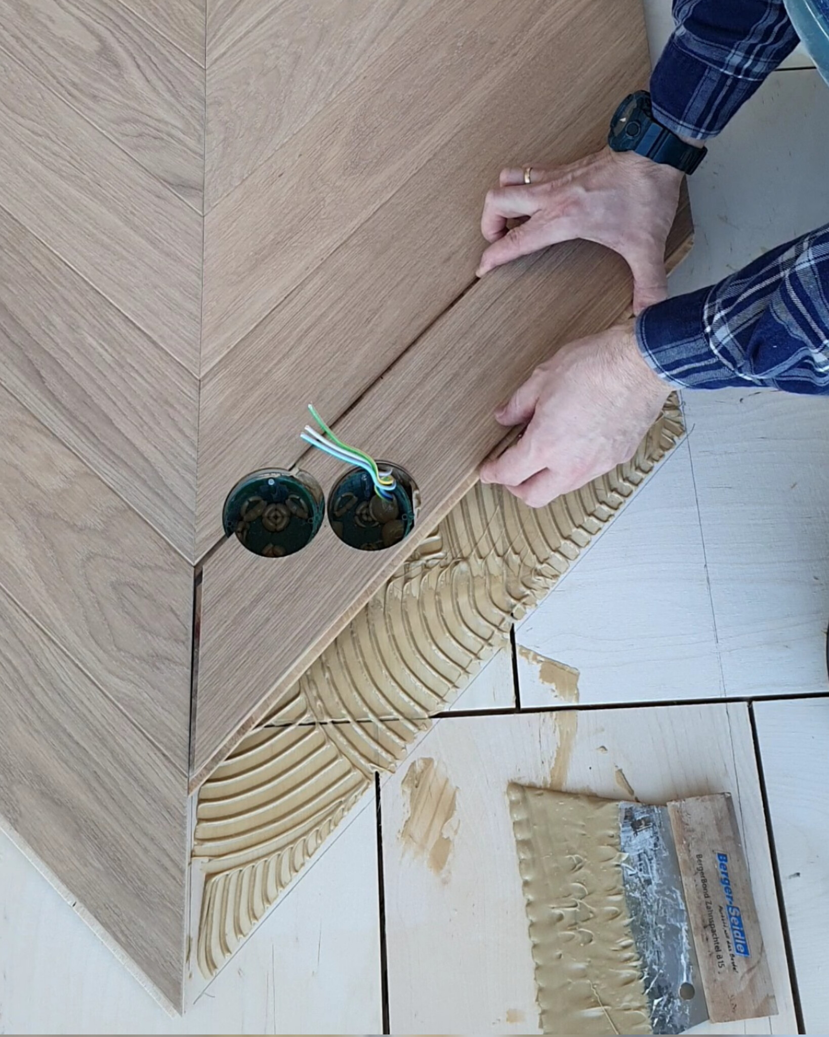 French chevron parquet fitted around floor socket openings during installation