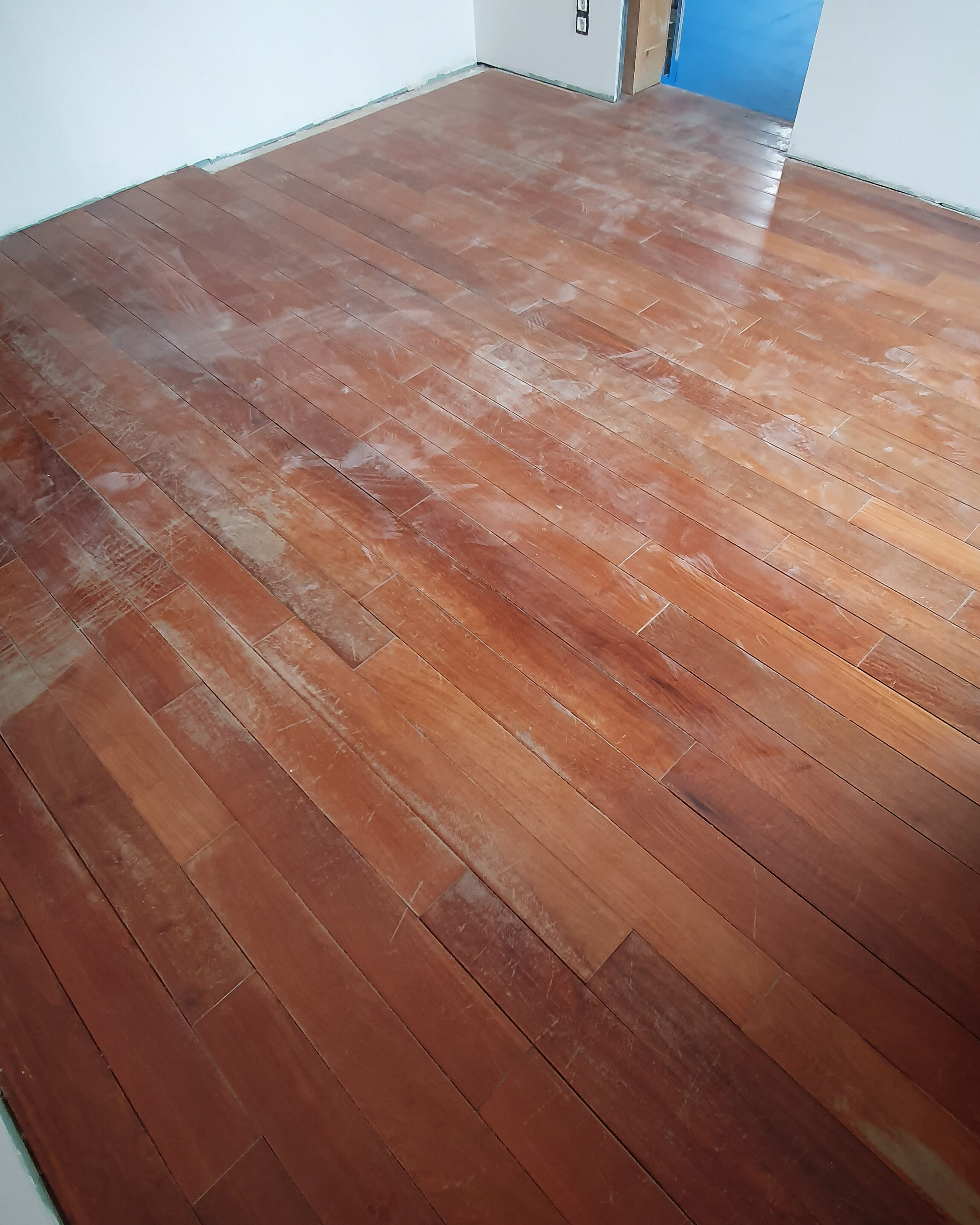 Worn exotic padauk flooring before sanding and restoration