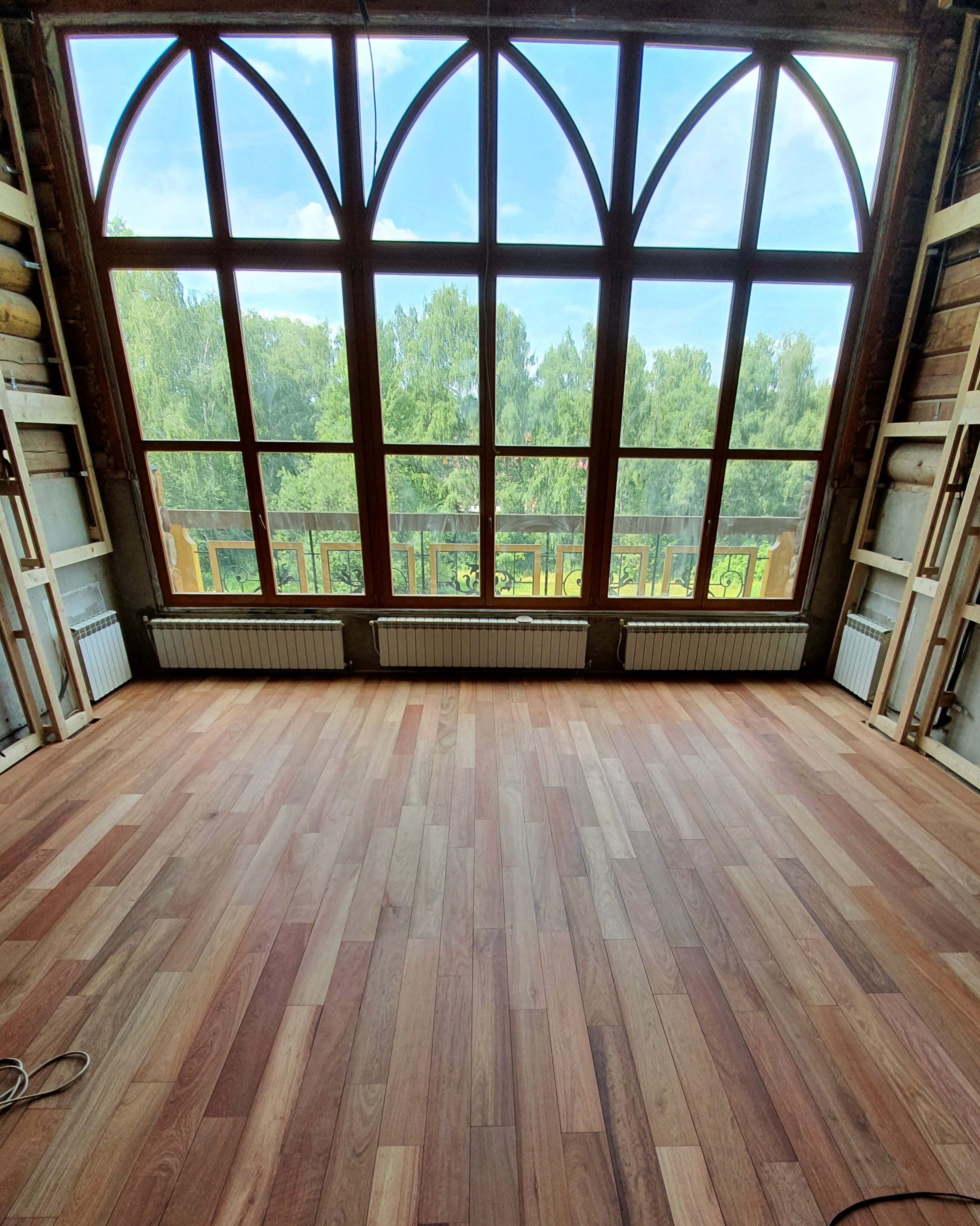 Restored padauk floor in a large room with full-height windows
