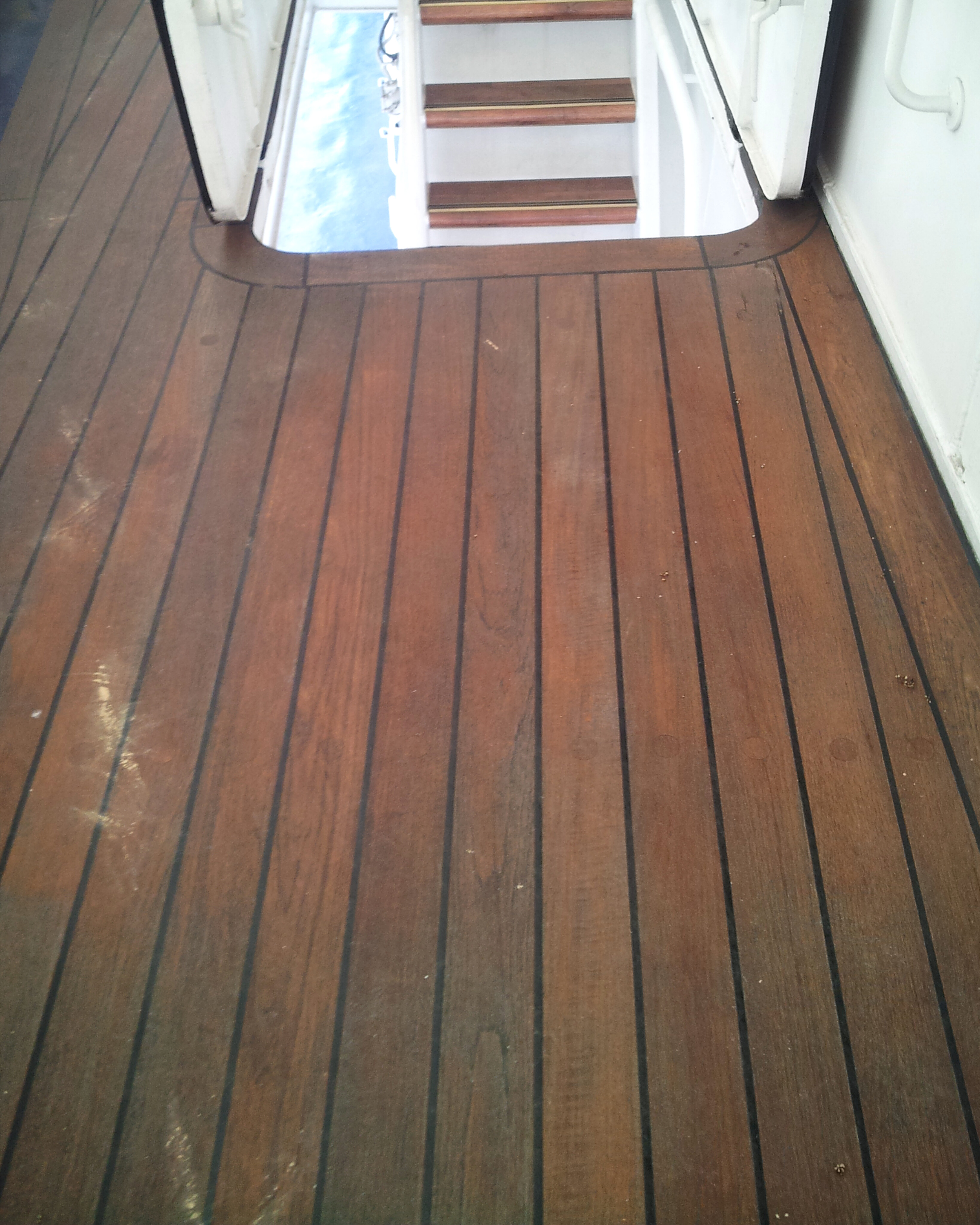 Weathered teak deck around a ship stair opening before restoration