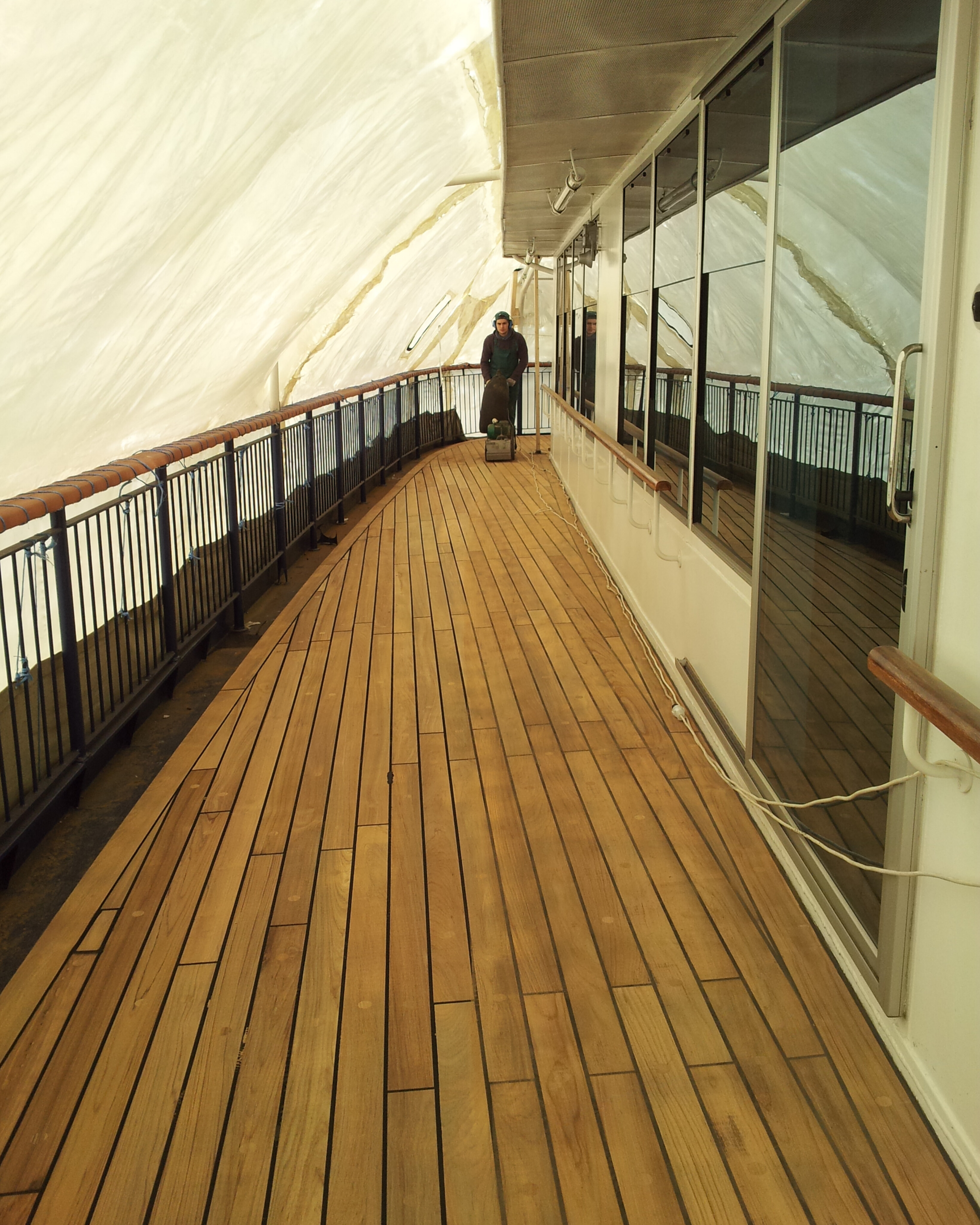 Restored teak ship deck on a long covered vessel passageway