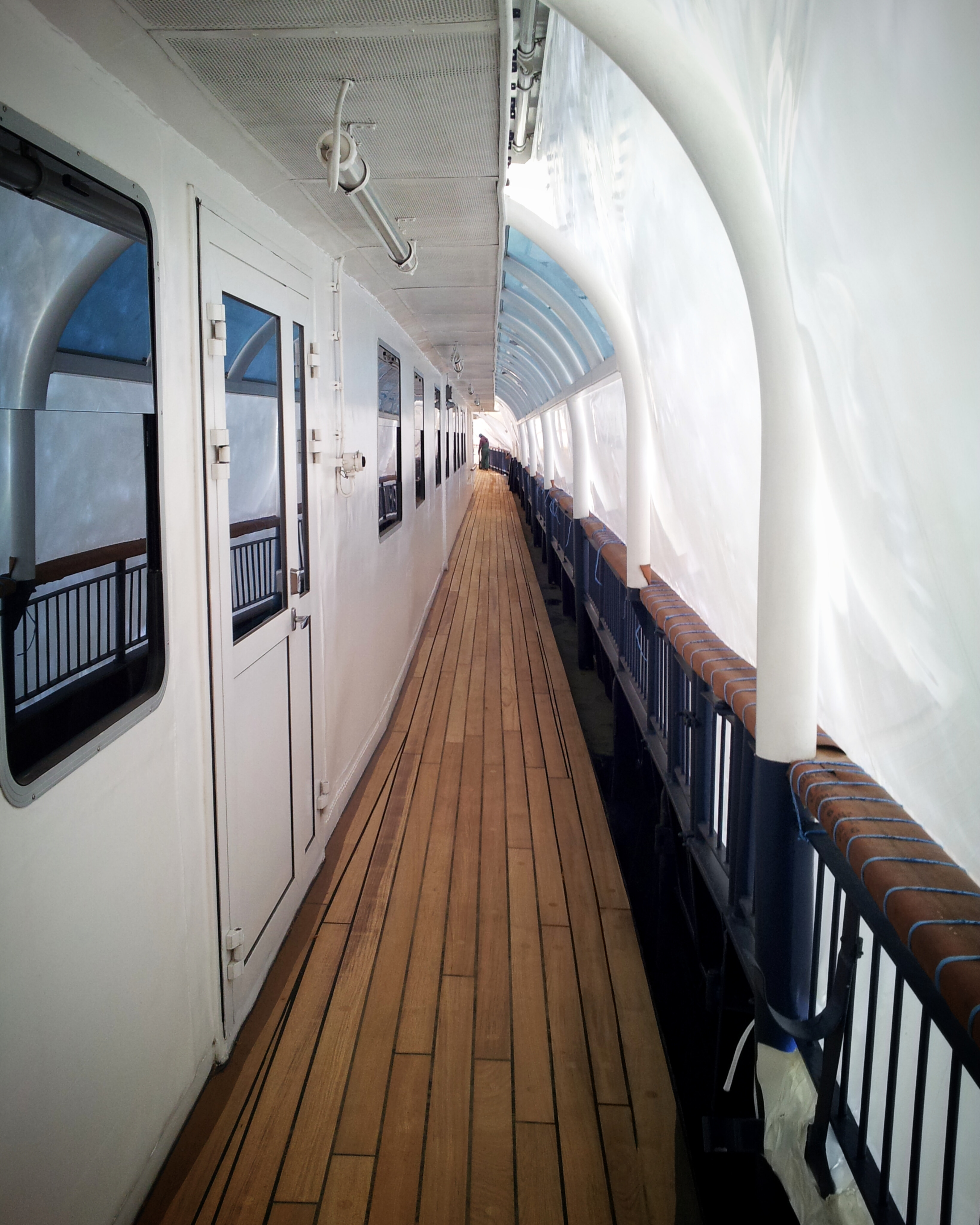 Restored teak deck along a narrow covered ship passage