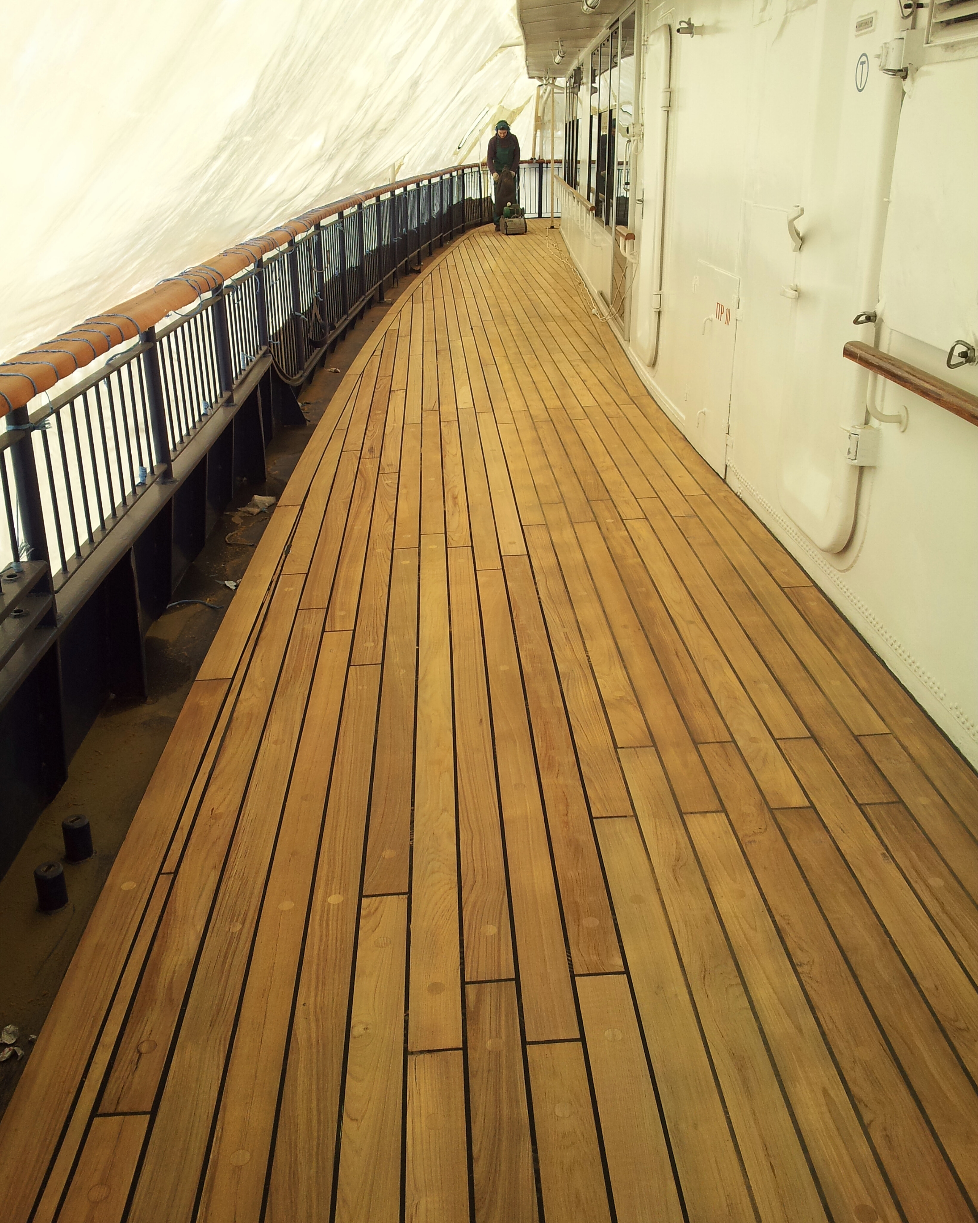 Wide restored ship deck section with teak planks and dark marine seams