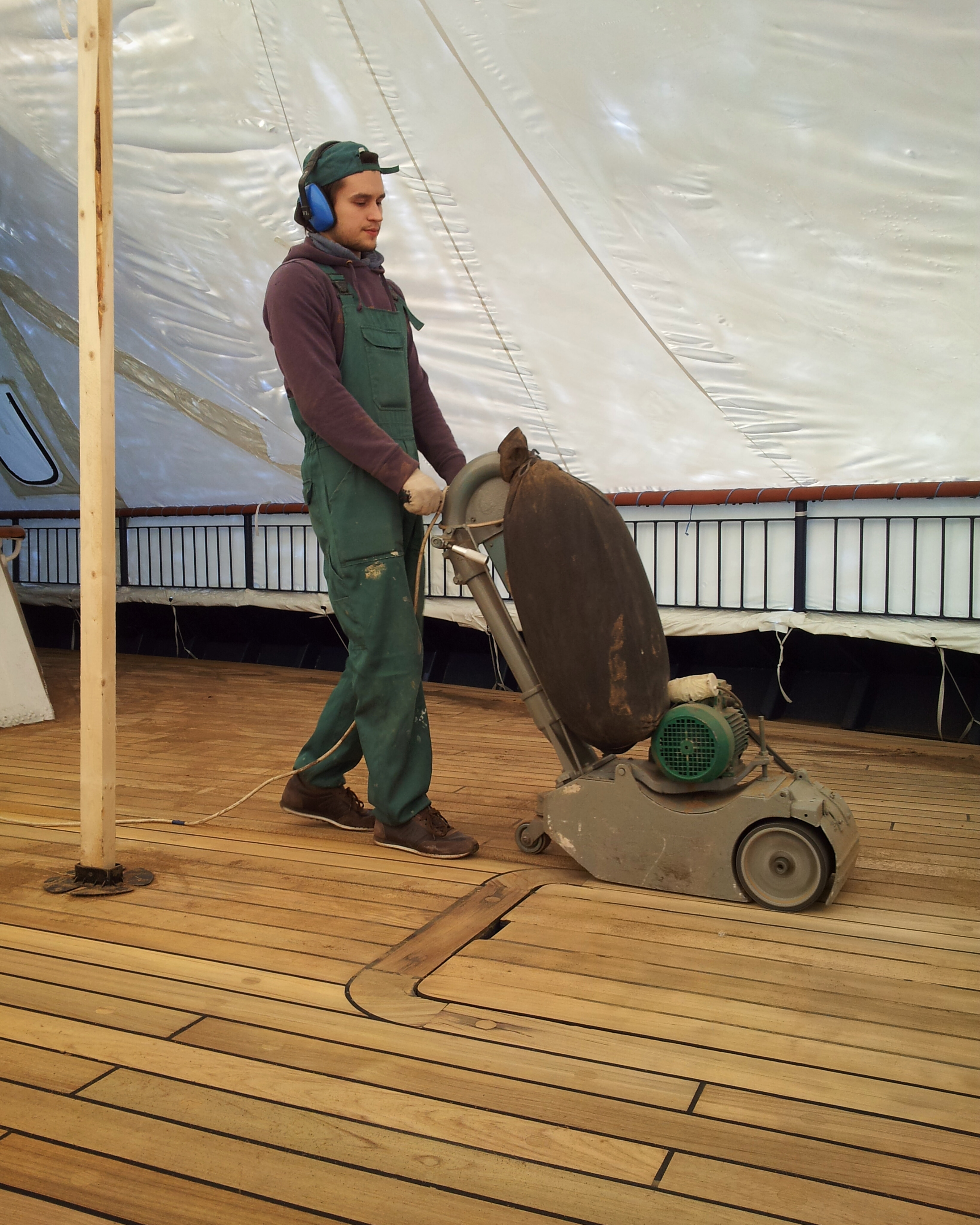 Sanding machine in use on a teak ship deck during restoration