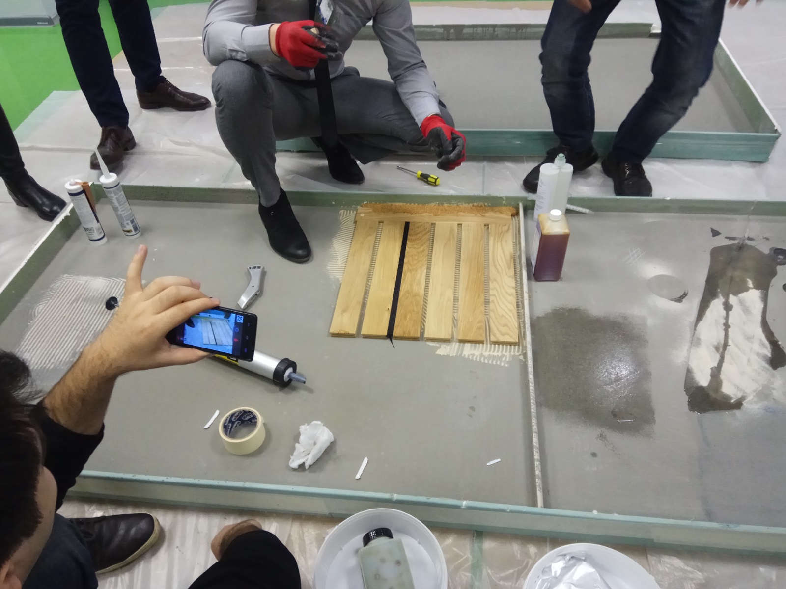 Hands-on adhesive demonstration during a flooring seminar.